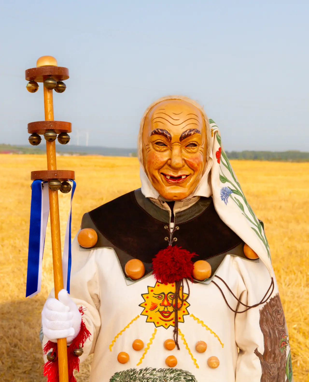 Weckazwinger mit lachender Maske, Zipfelmütze und Schellenstock