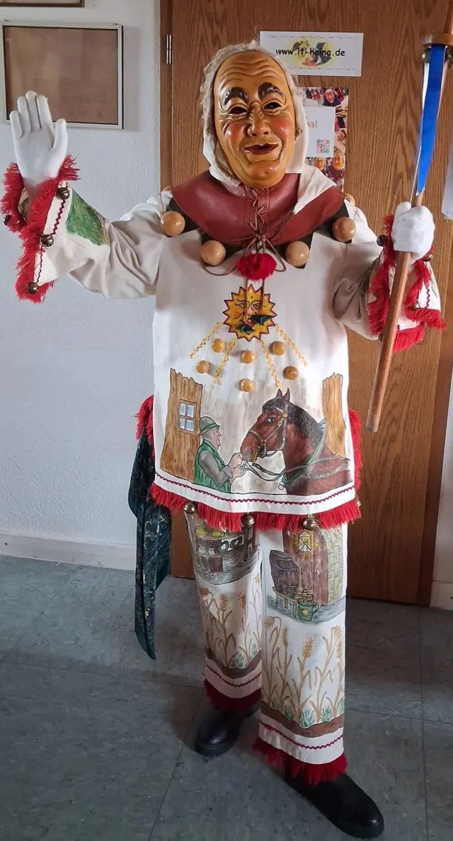 Weckazwinger mit weißen Handschuhen, schwarzen Schuhen, festgebundener Mütze und Schellenstock