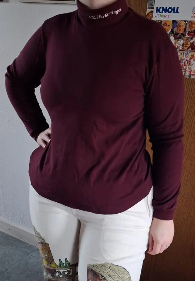 Weinroter Rollkragenpullover mit Aufdruck der Narrenzunft, darunter die weiße Häshose
